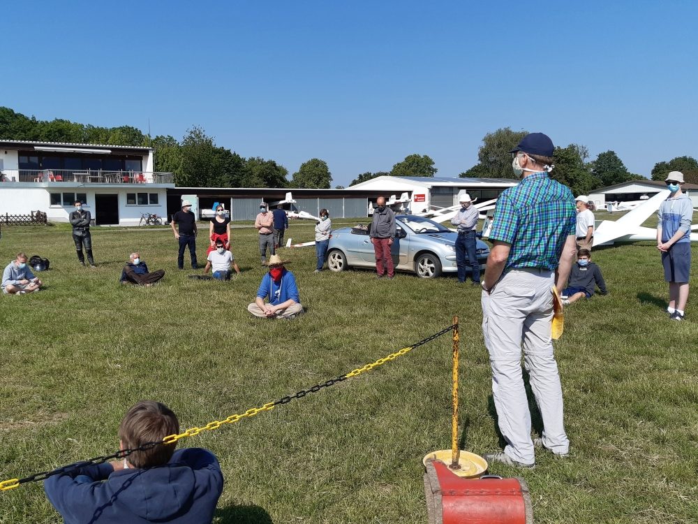 Briefing mit Mund-Nasen-Maske und Sicherheitsabstand